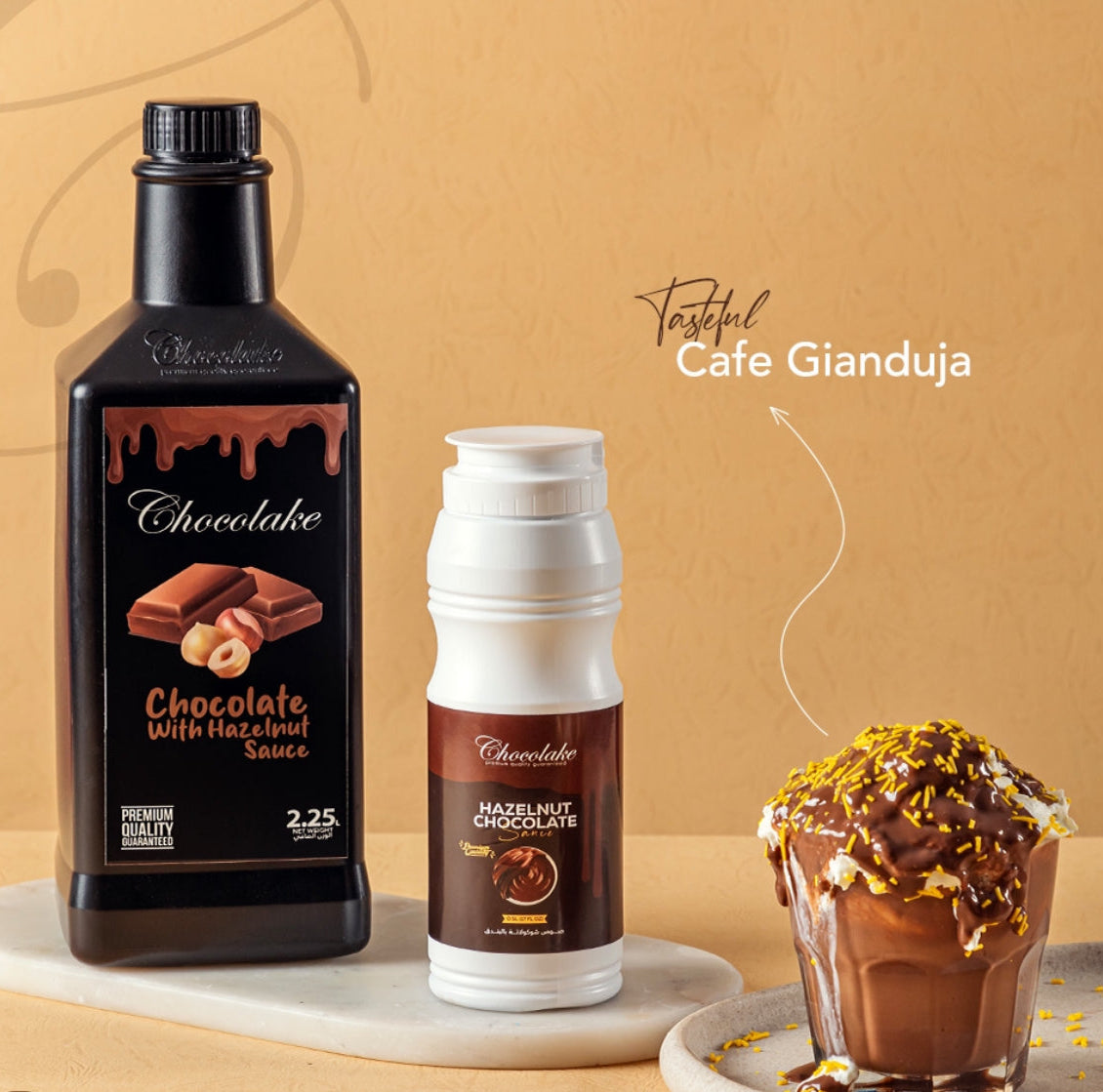 Bottle of Chocolake with Hazelnut Sauce and a cup of Cafe Gianduja dessert on a beige background.